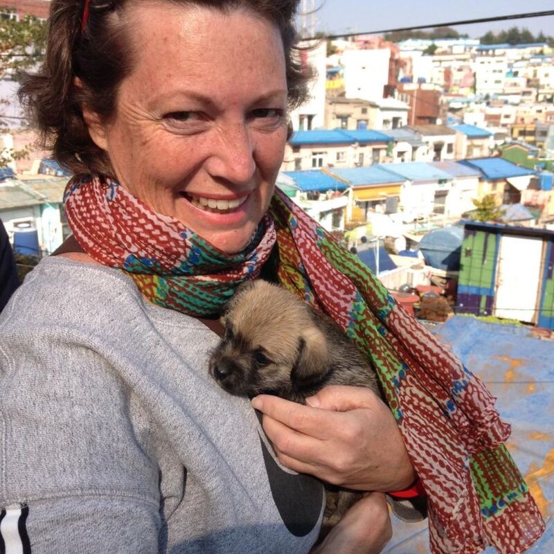 Annie holding a puppy in some town overseas